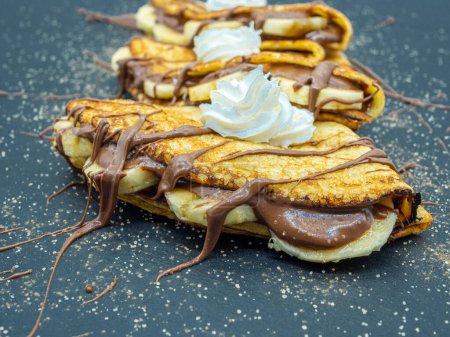 Photo for Delicious thin pancakes with chocolate spread and slices of banana, side view - Royalty Free Image