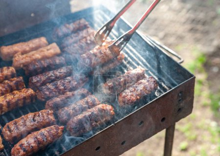 Photo for Small Romanian minced meatrolls called mici or mititei, similar to serbian cevapi, fresh balkan skinless sausages, cooked outside on the barbecue - Royalty Free Image