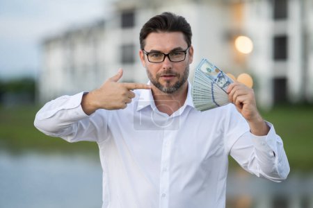 Attractive man is holding cash money in one hand. Joyful man with banknotes of money in his hands. Big financial luck and success, profit and cash. Rich man hands holding cash money