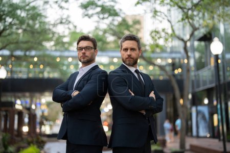  businessmans in casual attire looking at camera. two businessmen in suits with their arms crossed looking at the camera. sstkBusiness. two successful businessmen in suits with their arms crossed 