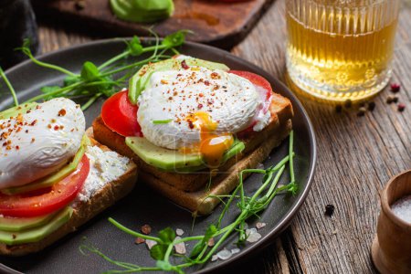 Téléchargez les photos : Toast aux œufs pochés, tomates et avocat. Petit déjeuner sain - en image libre de droit