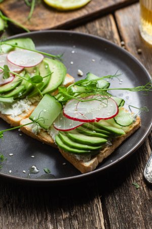 Photo for White bread toasts with cream cheese, avocado, cucumber and radish in a plate - Royalty Free Image
