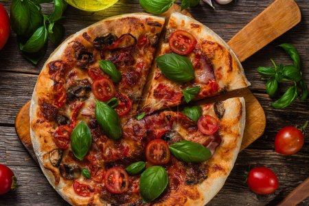 Téléchargez les photos : Pizza appétissante. Pizza au jambon, champignons et tomates sur fond de bois - en image libre de droit