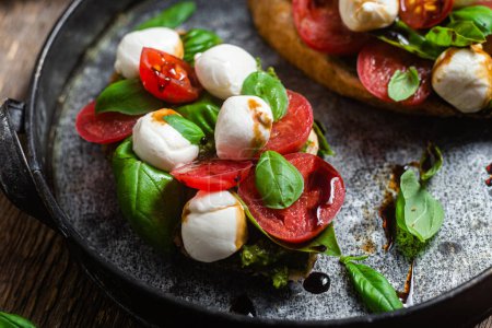 Téléchargez les photos : Bruschetta avec mozzarella, tomates, basilic et pesto dans une assiette. Bruschetta Caprese - en image libre de droit