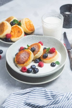 Photo for Cottage cheese pancakes with creamy sauce, raspberries and blueberries - Royalty Free Image