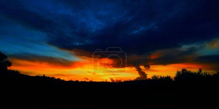 Foto de Puesta de sol rojo-naranja con nubes azules - Imagen libre de derechos