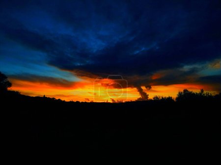 Foto de Puesta de sol rojo-naranja con nubes azules - Imagen libre de derechos