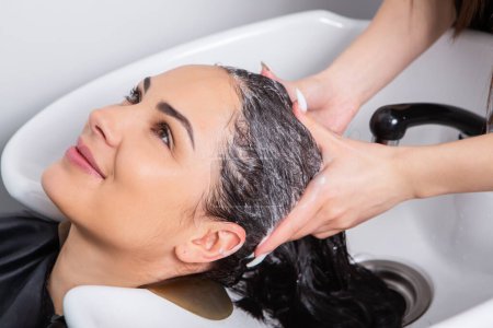 Téléchargez les photos : Professional hairdresser washing hair of young woman in beauty salon. close up of woman's hair in beauty salon, hairstyle concept - en image libre de droit