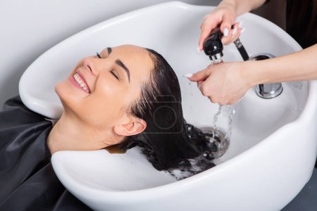 Téléchargez les photos : Professional hairdresser washing hair of young woman in beauty salon. close up of woman's hair in beauty salon, hairstyle concept - en image libre de droit