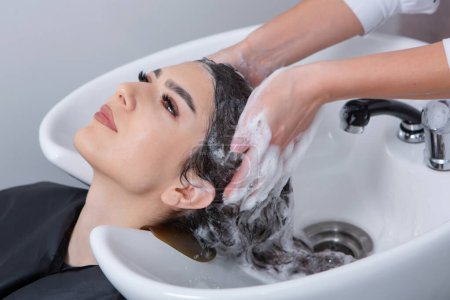 Foto de Professional hairdresser washing hair of young woman in beauty salon. close up of woman's hair in beauty salon, hairstyle concept - Imagen libre de derechos