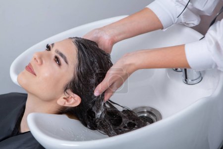 Foto de Professional hairdresser washing hair of young woman in beauty salon. close up of woman's hair in beauty salon, hairstyle concept - Imagen libre de derechos