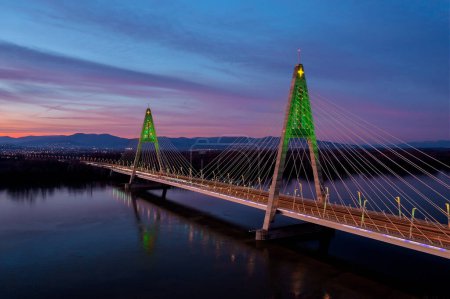 Téléchargez les photos : Vue aérienne sur le pont Megyeri illuminé dans une rare décoration de Noël au coucher du soleil. - en image libre de droit