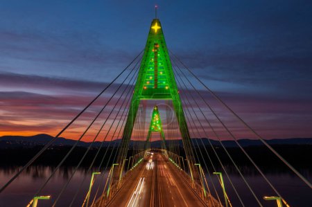 Téléchargez les photos : Vue aérienne rapprochée sur le pont Megyeri illuminé dans une rare décoration de Noël avec un magnifique coucher de soleil à l'arrière-plan. - en image libre de droit