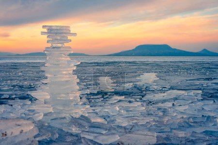 Téléchargez les photos : Fonyod, Hongrie - Beaux icebergs sur la rive du Balaton gelé. Badacsony et Gulacs avec un spectaculaire coucher de soleil nuageux en arrière-plan. - en image libre de droit