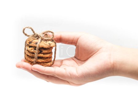 Stacked of chocolate chip cookies tied with twine rope on open hand isolated on white background clipping path