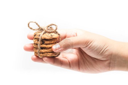 Hand holding stacked of chocolate chip cookies tied with twine rope isolated on white background clipping path