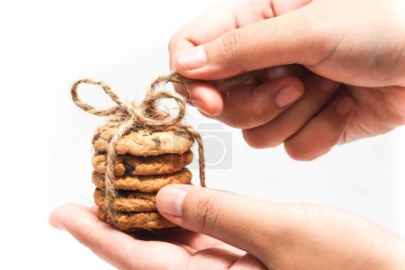Hand holding stacked of chocolate chip cookies untied the twine rope isolated on white background clipping path