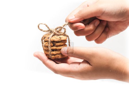 Hand holding stacked of chocolate chip cookies untied the twine rope isolated on white background clipping path