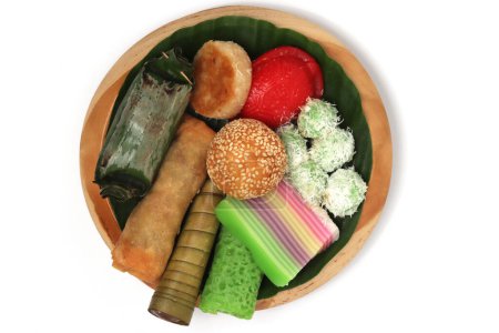 Various kinds of Jajan Pasar, traditional Indonesian market snacks, on the wooden plate with banana leaves isolated on white background clipping path