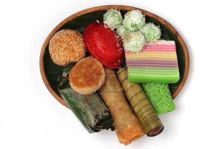 Various kinds of Jajan Pasar, traditional Indonesian market snacks, on the wooden plate with banana leaves top view isolated on white background clipping path