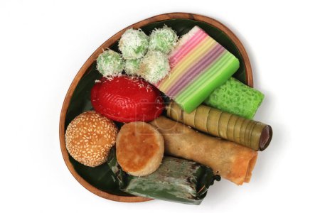 Téléchargez les photos : Différents types de Jajan Pasar, snacks traditionnels du marché indonésien, sur la plaque de bois avec des feuilles de banane vue de dessus isolé sur fond blanc chemin de coupe - en image libre de droit