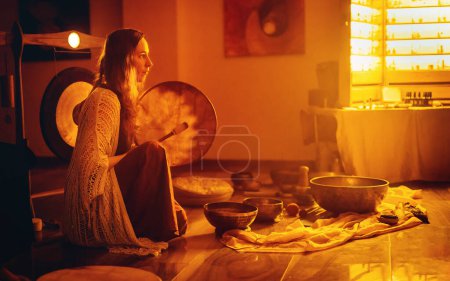 Photo for Beautiful woman playng on tibetan bowl and shaman drum, ceremonial space - Royalty Free Image