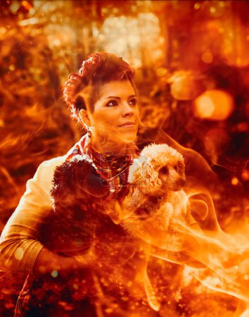 Téléchargez les photos : Une femme, canalisant l'esprit de la sorcière du feu, berce un chien au milieu de flammes flamboyantes dans les bois mystiques. - en image libre de droit