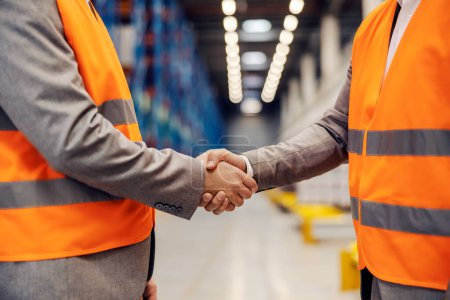 Closeup of business partners shaking hands in warehouse.