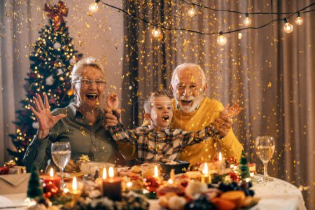 Aufgeregte Großeltern feiern Weihnachten und Silvester zu Hause mit Enkel.