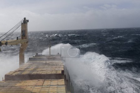 Photo for Cargo vessel with deck cargo at stormy sea. View from navigational bridge. Stormy sea, Bad weather. Gale. Rough sea. - Royalty Free Image