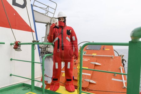 Photo for Seaman wearing Immersion Suit on Muster station. Abandon ship drill. Free fall boat. Cargo vessel. - Royalty Free Image