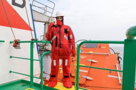 Photo for Seaman wearing Immersion Suit on Muster station. Abandon ship drill. Free fall boat. Cargo vessel. - Royalty Free Image