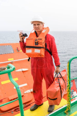 Photo for Seaman wearing lifejacket with vhf radio on Muster station. Abandon ship drill. Free fall boat. Cargo vessel. - Royalty Free Image