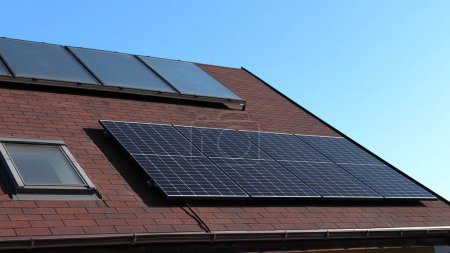 Foto de El techo de la casa con paneles termosolares y fotovoltaicos. Casa autosuficiente. Energía verde. Acuerdo verde. - Imagen libre de derechos