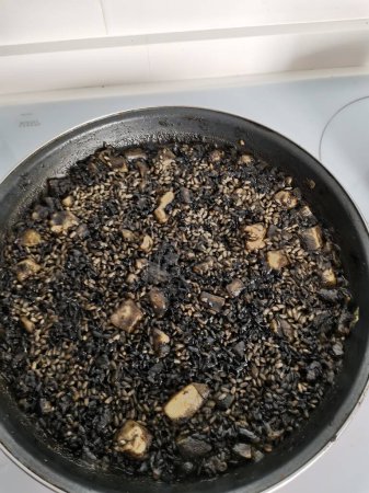 Arroz Negro Black Rice. Traditionelles valencianisches Gericht. Der schwarze Reis ähnelt der Paella mit Meeresfrüchten, wird aber mit Tintenfischtinte gekocht.