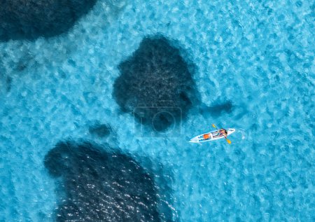 Téléchargez les photos : Vue aérienne du kayak avec l'homme en mer bleue lors d'une journée ensoleillée en été. Homme et femme en canot flottant dans de l'eau claire et azur. Sardaigne, Italie. Paysage tropical. Superbe planche. Voyage actif. Vue du dessus - en image libre de droit