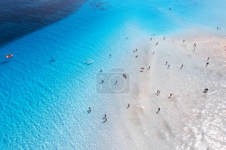 Foto de Vista aérea de la increíble costa del mar. Vista superior desde el dron de playa con arena blanca, nadando personas en agua azul transparente en el día soleado. Verano en la playa de La Pelosa, Cerdeña, Italia. Paisaje tropical - Imagen libre de derechos