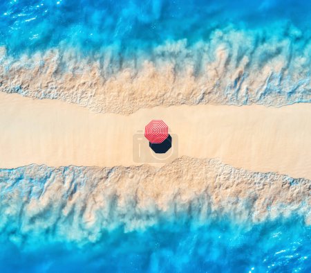 Photo for Aerial view of transparent blue sea with waves on the both sides and sandy beach with colorful red umbrella at sunset. Top view of sandbank. Summer travel. Tropical landscape with white sand and ocean - Royalty Free Image