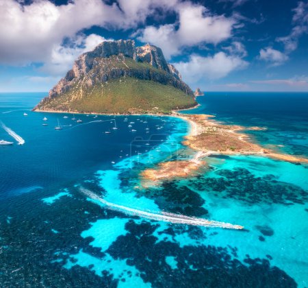 Aerial view of high mountain, yachts and floating speed boat on blue sea, sky with clouds in summer. Sandy beach, azure water on Tavolara island in Sardinia, Italy. Top drone view. Colorful seascape