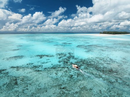 Vue aérienne du bateau flottant en eau claire et azurée le jour d'été. Île de Mnemba, Zanzibar. Vue du dessus du yacht, banc de sable à marée basse, mer bleu clair, sable, ciel nuageux. Idéal pour les vacances, Voyage