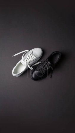 White and black leather shoes on a black background. sneakers with laces. New shoes. Vertical image.