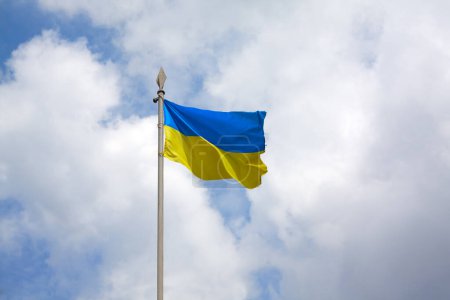 Photo for Ukrainian flag on a flagpole in the wind develops in the background of the sky. - Royalty Free Image