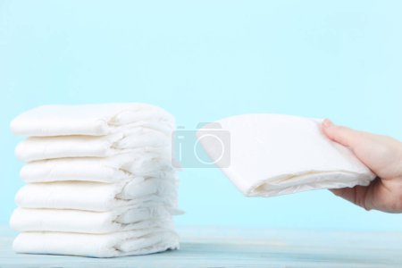 Photo for Baby diapers with female hand on blue background - Royalty Free Image