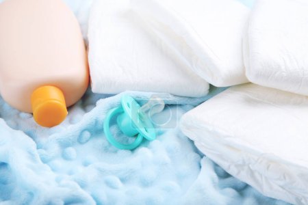 Téléchargez les photos : Couches pour bébés avec biberon et sucette sur fond bleu - en image libre de droit