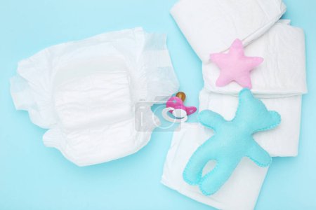 Photo for Baby diapers with bear, star toy and pacifier on blue background - Royalty Free Image