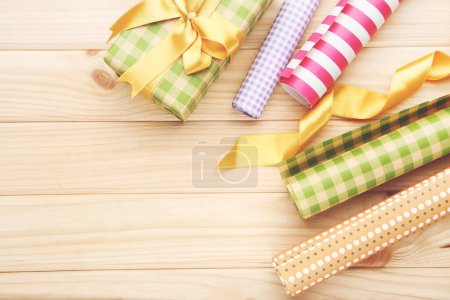 Téléchargez les photos : Rouleaux de papier artisanal avec boîte cadeau et ruban sur fond en bois - en image libre de droit