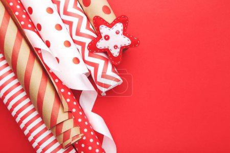 Téléchargez les photos : Rouleaux de papiers artisanaux avec étoile en tissu sur fond rouge - en image libre de droit