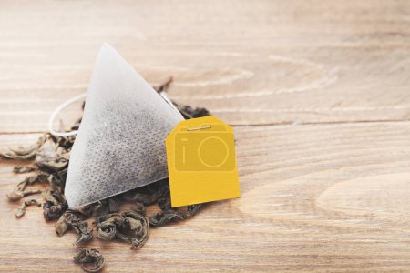 Photo for Tea bag with scattered tea on wooden table - Royalty Free Image