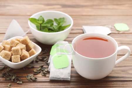 Foto de Taza de té con terrones de azúcar y hojas de menta sobre mesa de madera marrón - Imagen libre de derechos