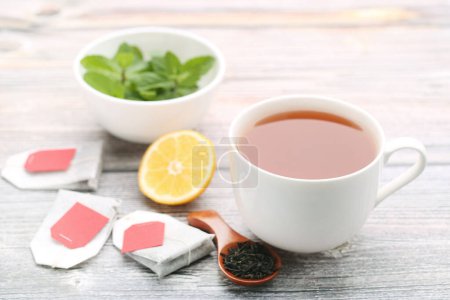 Photo for Cup of tea with lemon, mint leafs and spoon on wooden table - Royalty Free Image